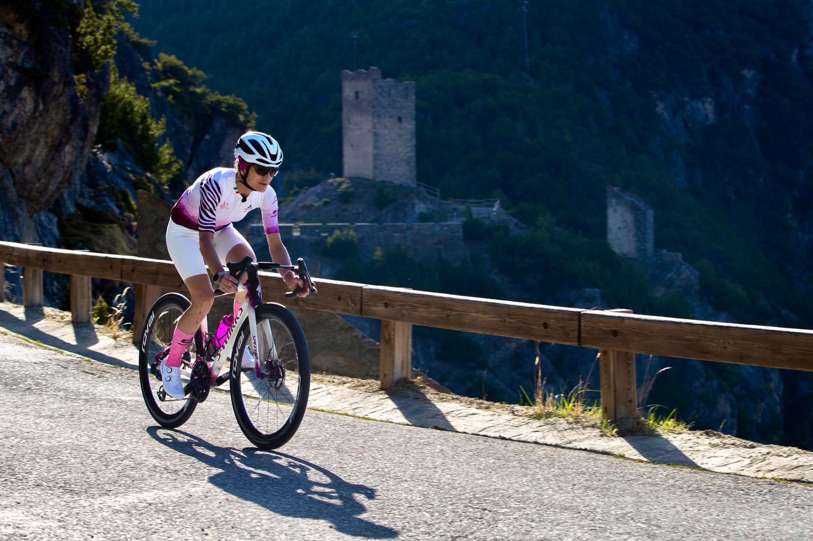 Atleta in bicicletta affronta i tornanti del Passo dello Stelvio, con un forte sullo sfondo
